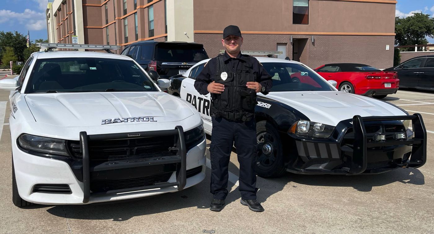 QSD officer standing between two patrol vehicles